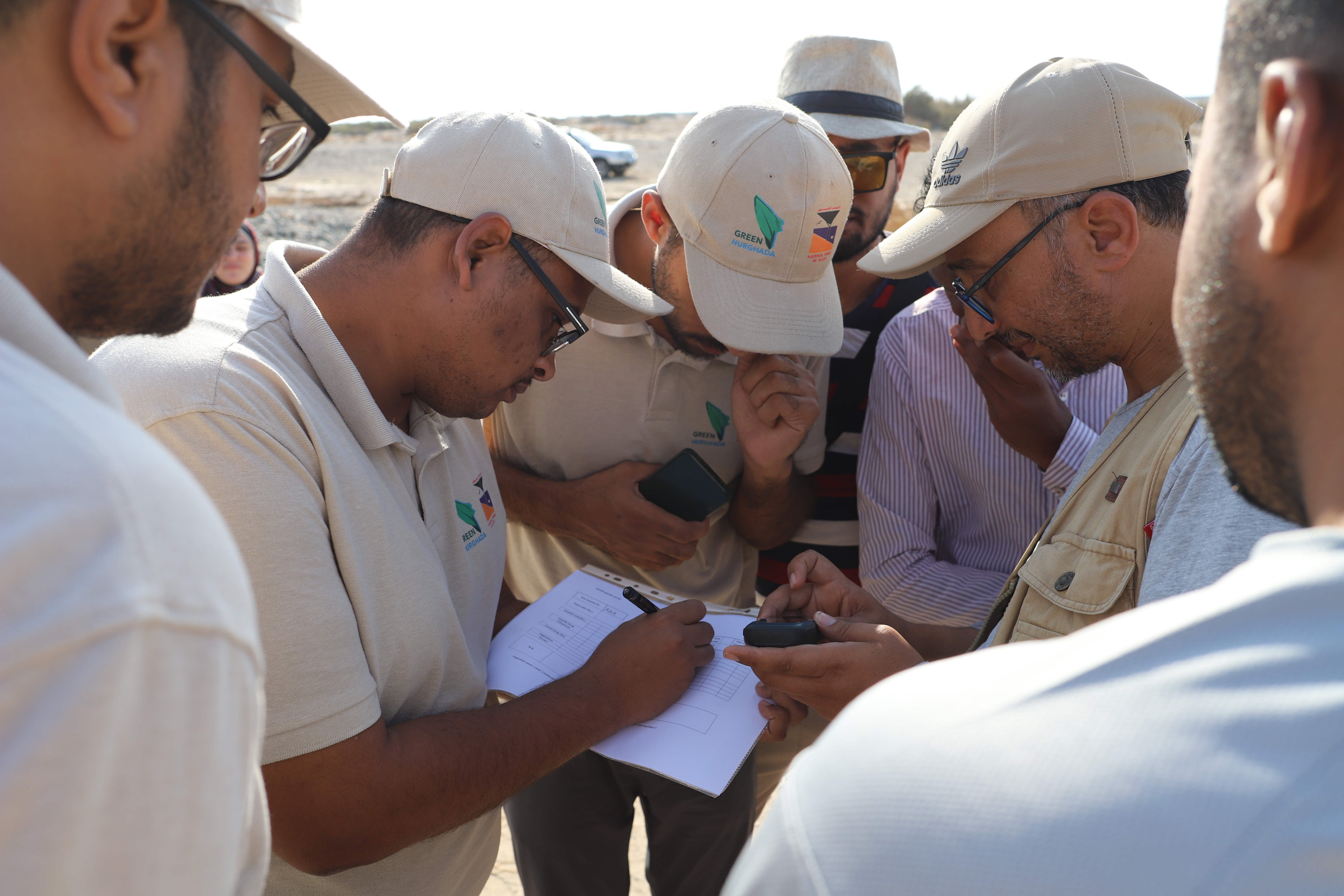 Field team recording GPS coordinates and survey data in the desert